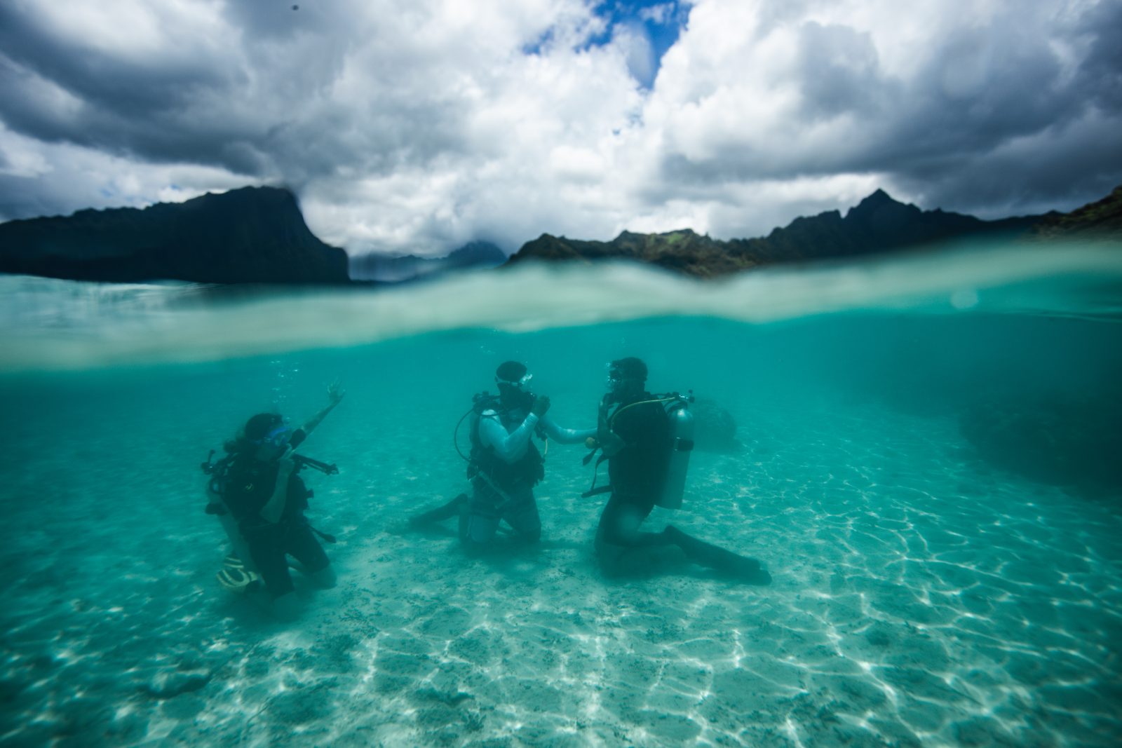 Half above, half below: divers in the lagoon, with Moorea's mountains behind